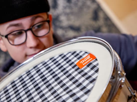 Miko Moon places a damper on a snare drum head.